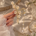 Zelpora gold-tone orchid hair clip with delicate white floral petals, pearl accents, and cascading pearl tassels.